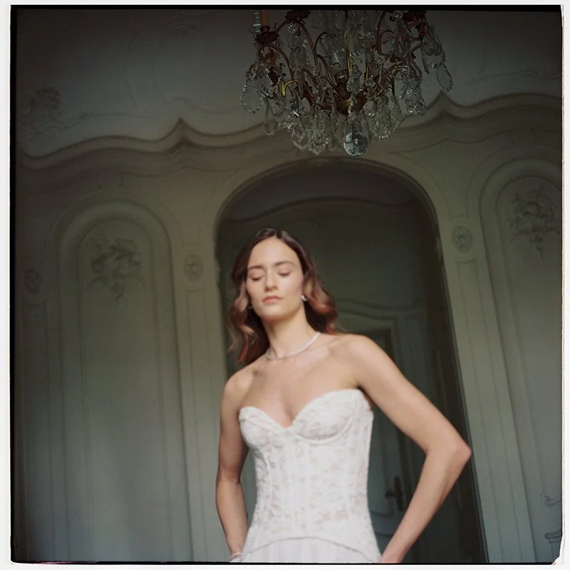 Eine Frau steht in einem weissen Kleid in einem Raum.