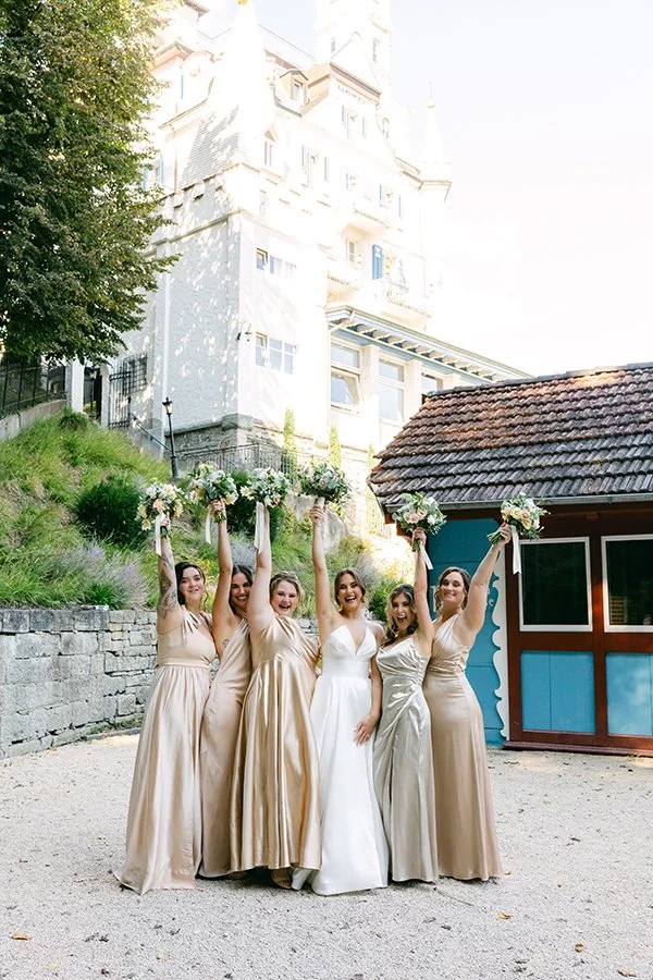 Sechs Frauen stehen nebeneinander in einem Garten und halten einen Blumenstrauss.