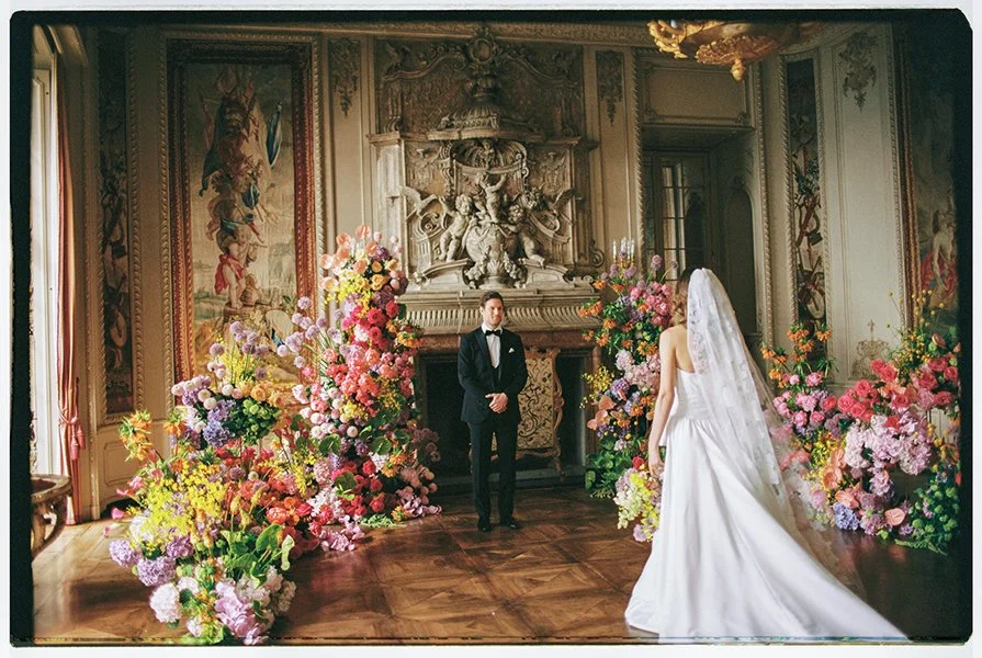 Eine Braut läuft zu ihrem Mann umgeben von bunten Blumen.