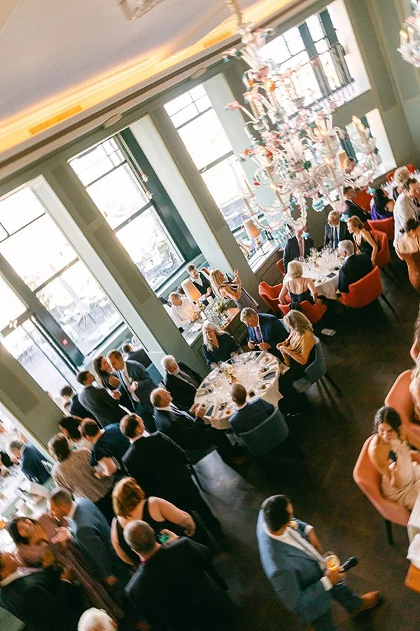 Ein Raum ist voll mit Menschen die an Tischen sitzen.