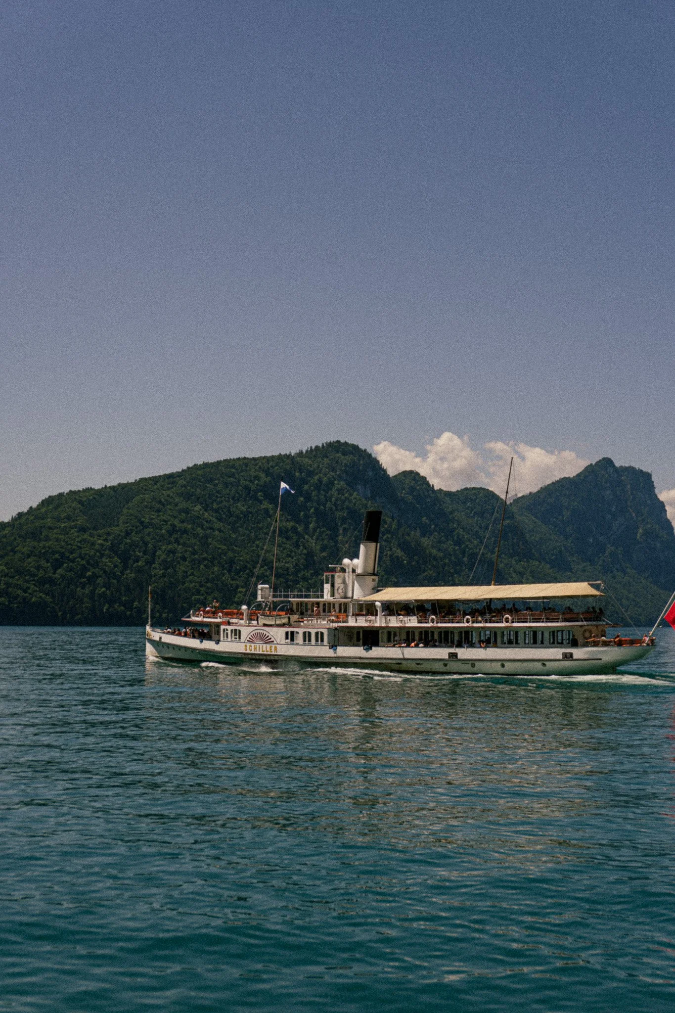 Ein Dampfschiff fährt auf dem Vierwaldstättersee bei Sonnenlicht.