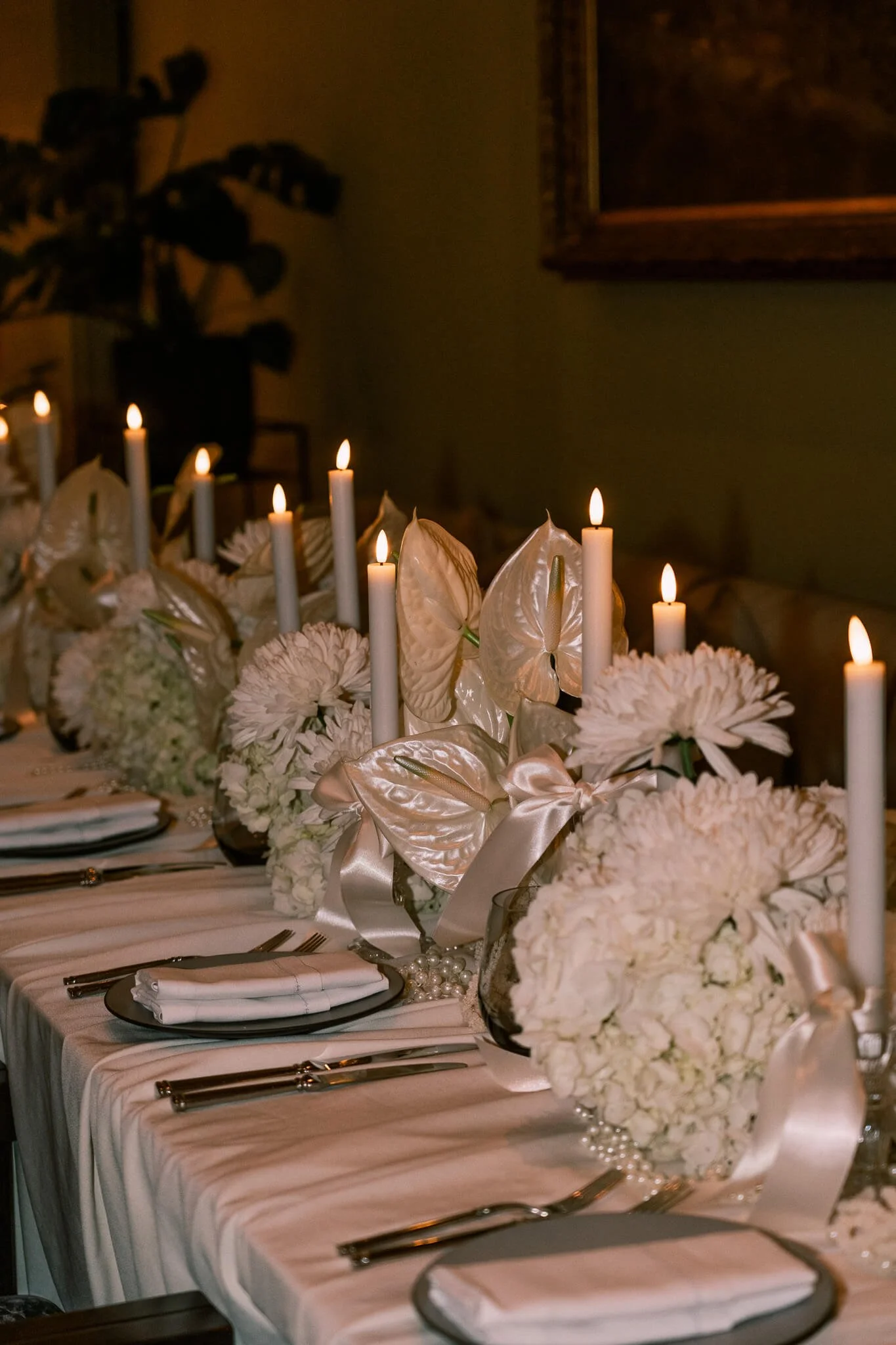 Viele weisse Blumen sind in der Mitte eines eingedeckten Tisches.