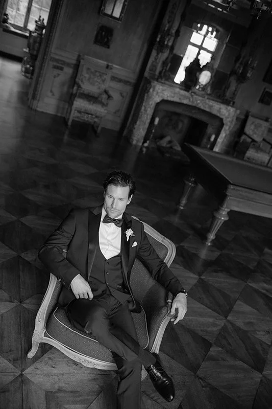 Ein Mann im Anzug sitzt ernst auf einem Sessel.