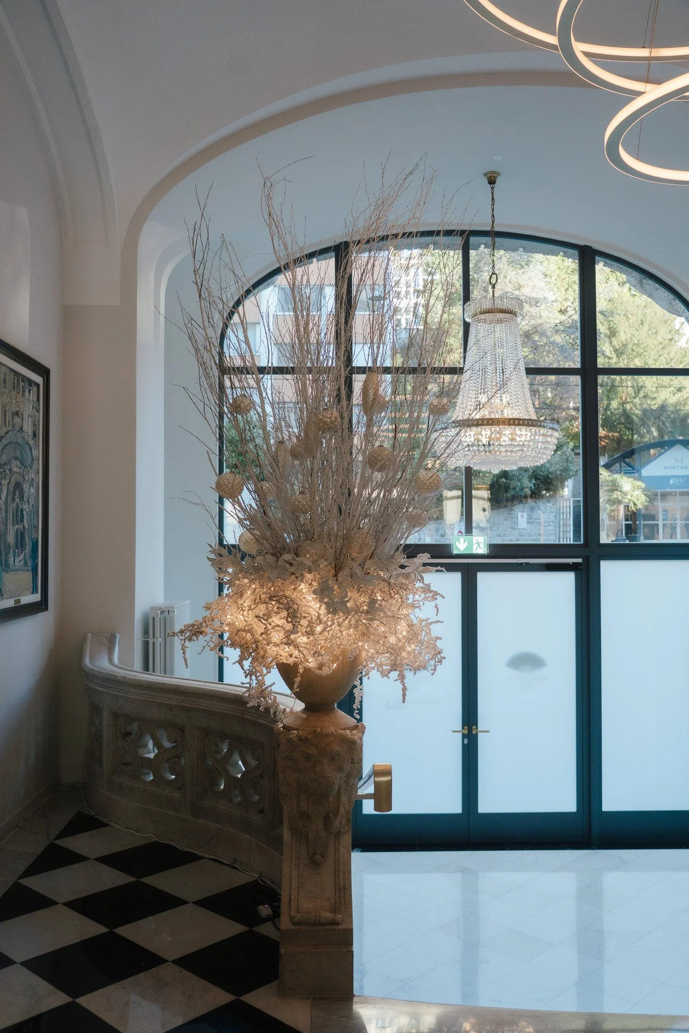 Ein grosses weisses Gesteck steht auf einer Säule in einem grossen hellen Raum.