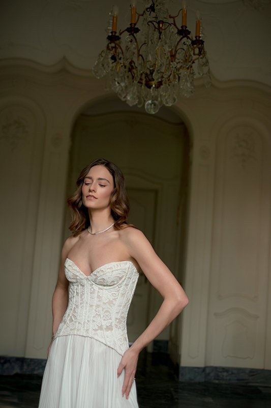 Eine Frau posiert in einem Brautkleid in einem hellen Raum.