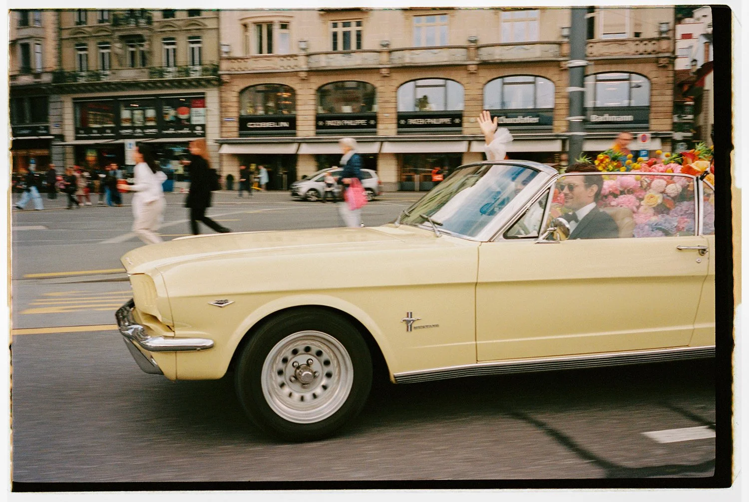 Ein fahrender hellgelber Oldtimer in Luzern.