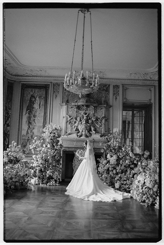 Eine Braut steht in einem grossen Raum mit vielen Blumen.