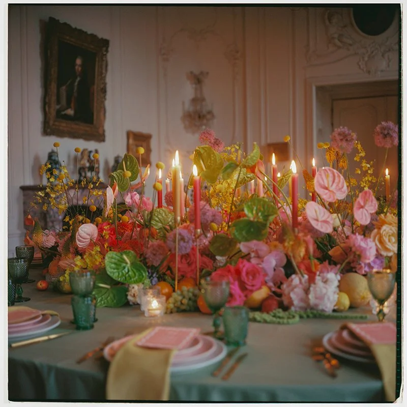 Ein eingedeckter Tisch ist dekoriert mit bunten Blumen und Kerzen.