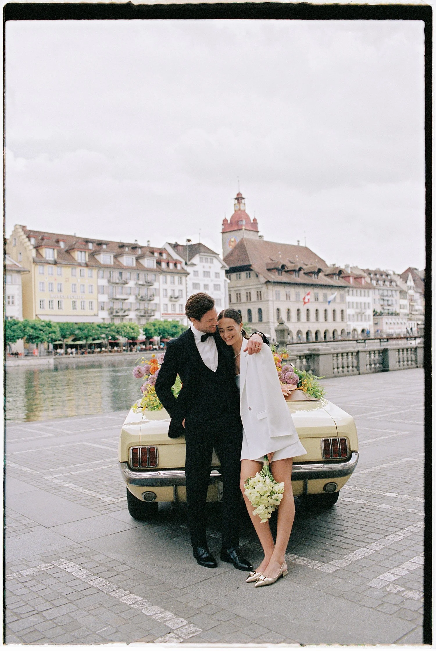 Ein Brautpaar steht vor einem alten Auto in der Stadt Luzern.