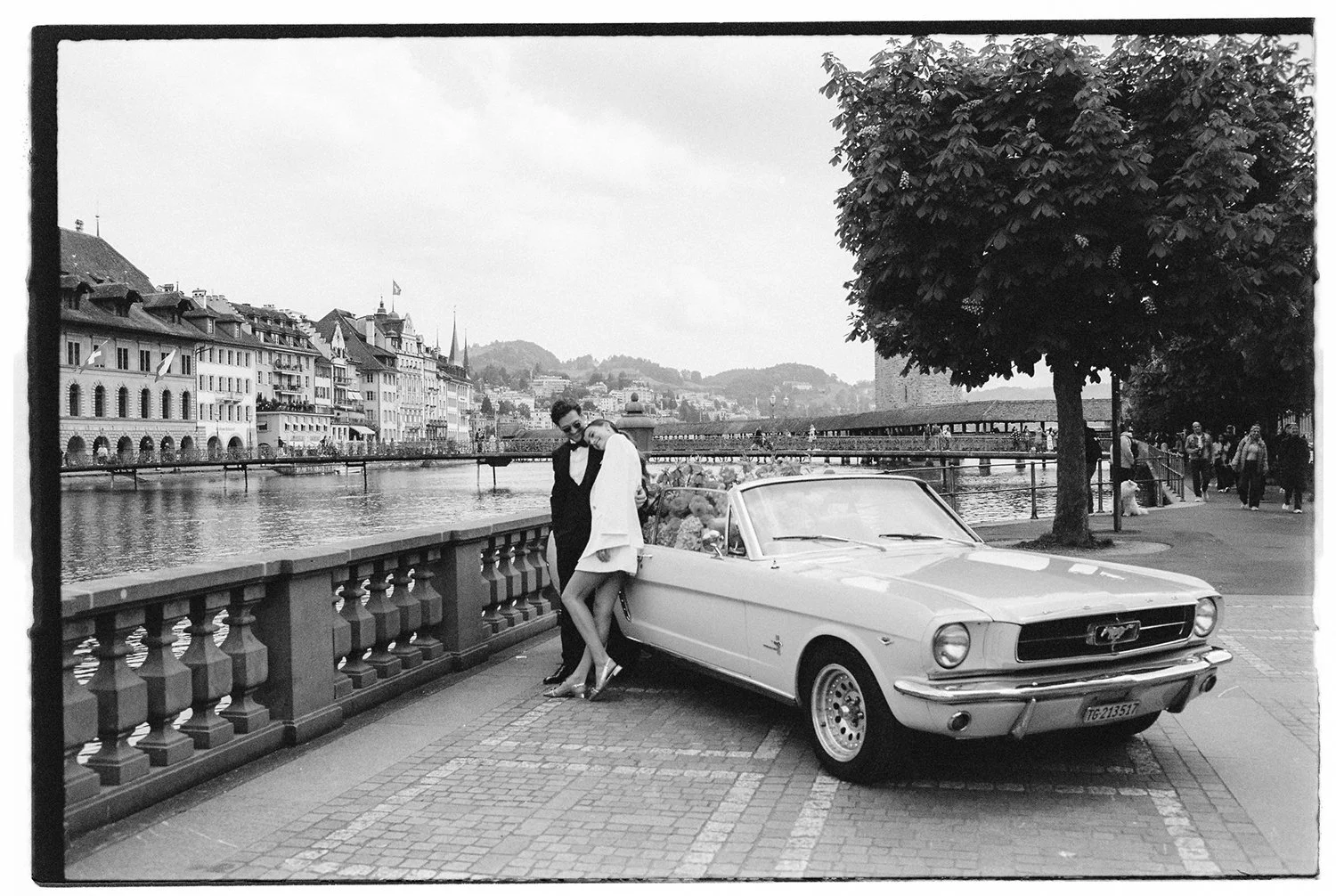 Ein schwarz weiss Bild von einem Ehepaar welches vor einem Oldtimer in Luzern steht.