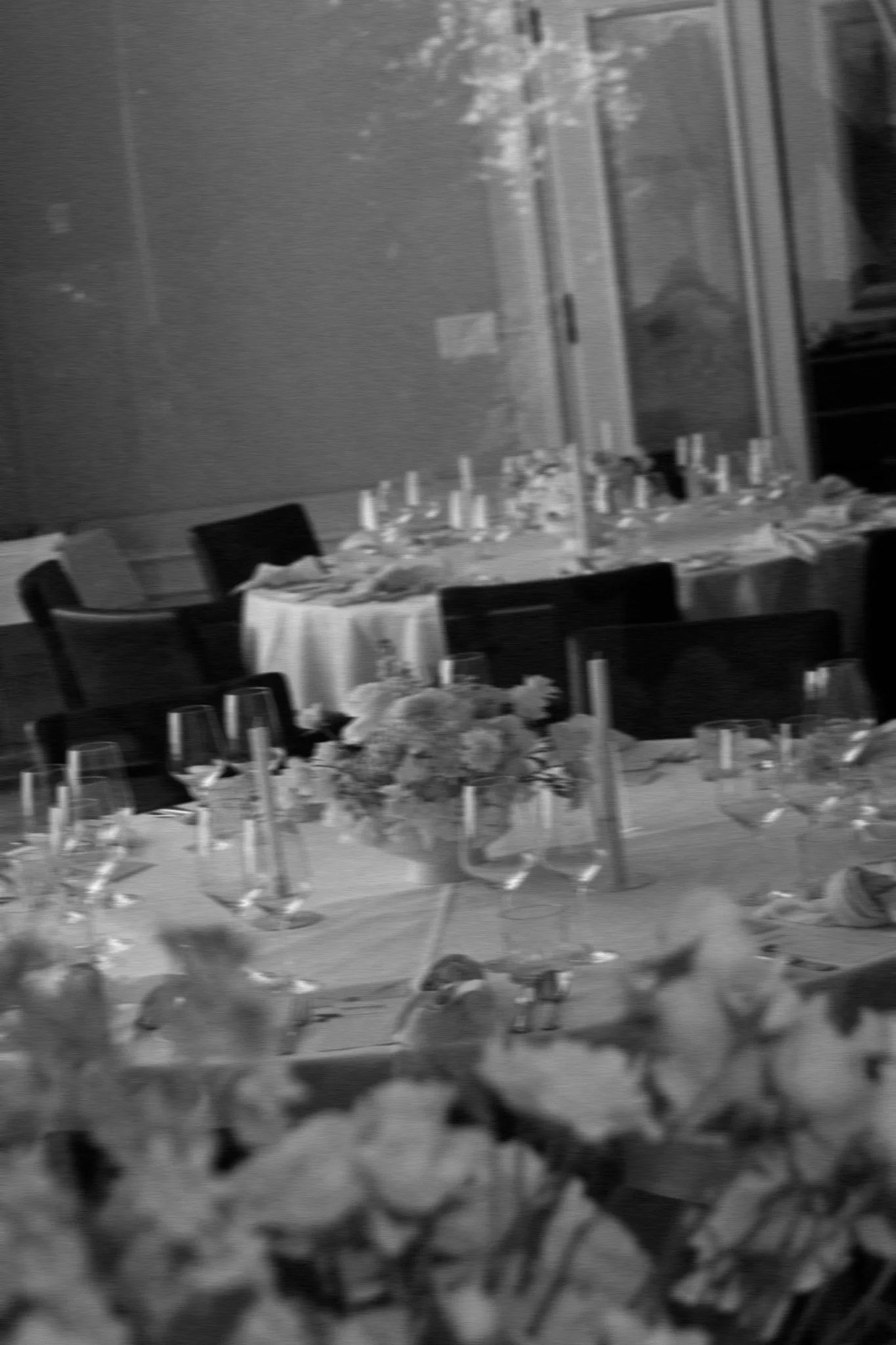 Ein Tisch ist eingedeckt mit einem Blumenbouquet und Stabkerzen in schwarz und weiss.