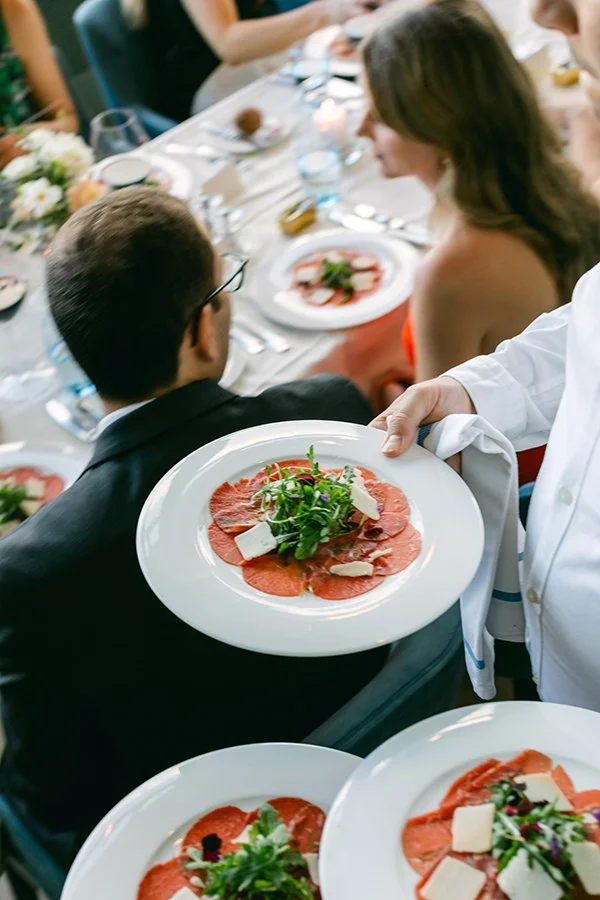 Ein Mann hält weisse Teller mit rotem Fleisch.