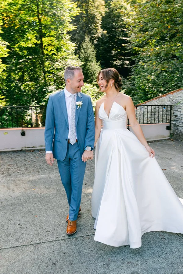 Ein Brautpaar läuft lachend und Hand in Hand nebeneinander.