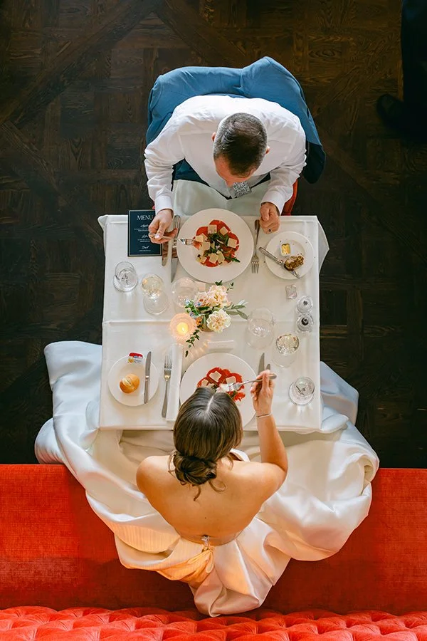 Ein Brautpaar sitzt an einem eingedeckten Tisch und isst.