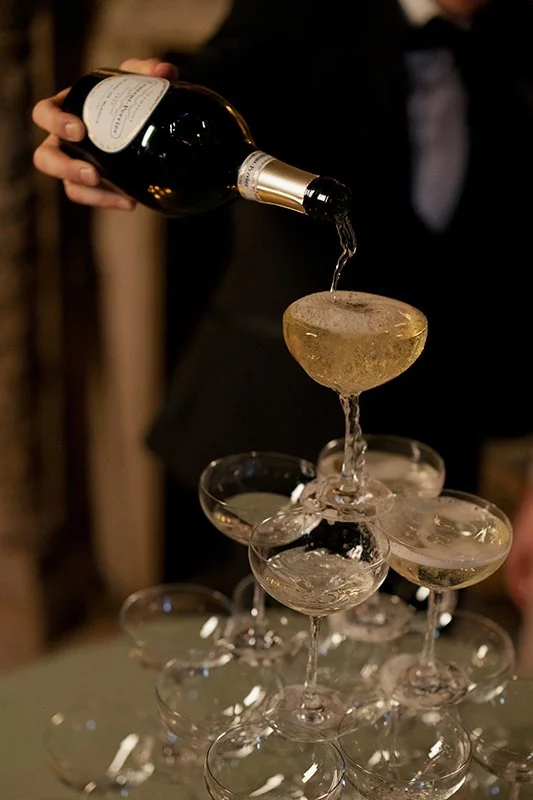 Champagner wird in einen Champagnerturm aus Gläsern geschüttet.