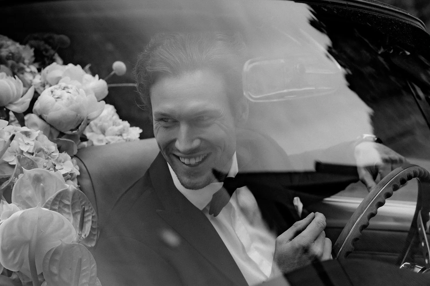 Ein Mann im Anzug sitzt hinter einer Scheibe und lacht.