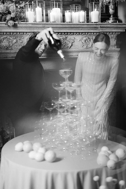 Ein Paar steht lachend hinter einem Champagnerturm.