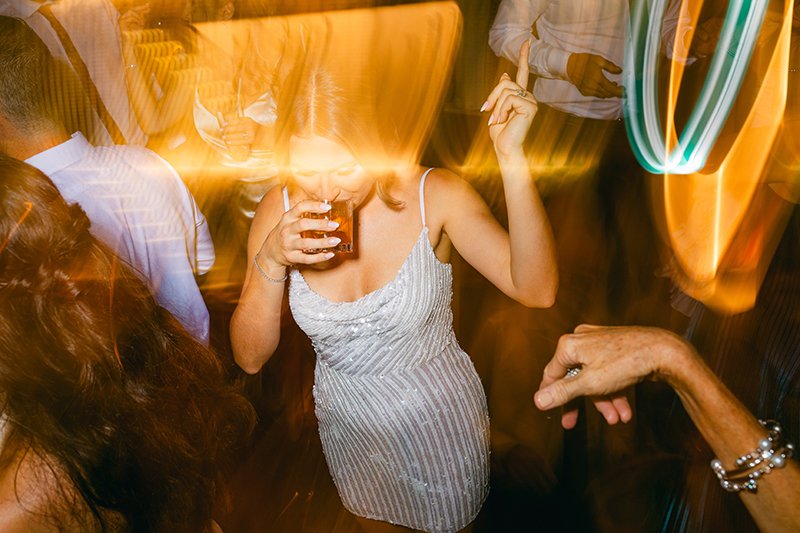 Eine Frau in einem silbernen Kleid ist tanzend am trinken.