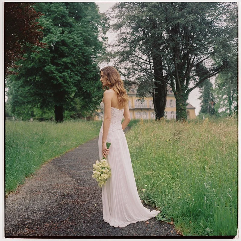 Eine Braut steht mit einem Brautstrauss auf einem Fe