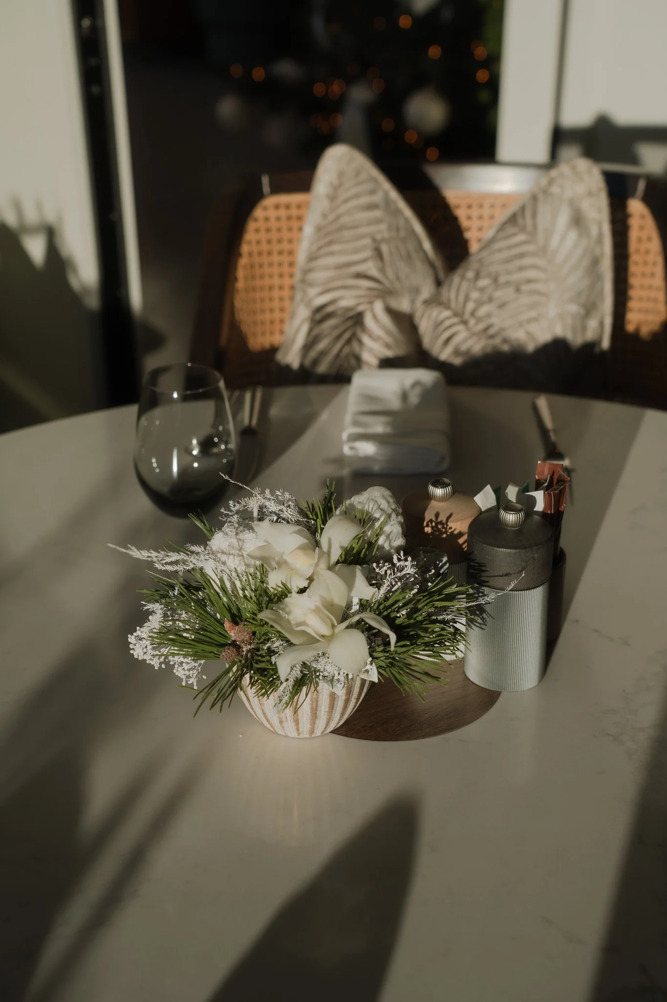 Ein florales Gesteck steht auf einem weissen Tisch im Sonnenlicht.