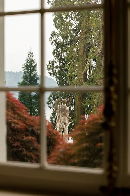 Eine Porzelanfigur steht umgeben von Bäumen in einem Garten.