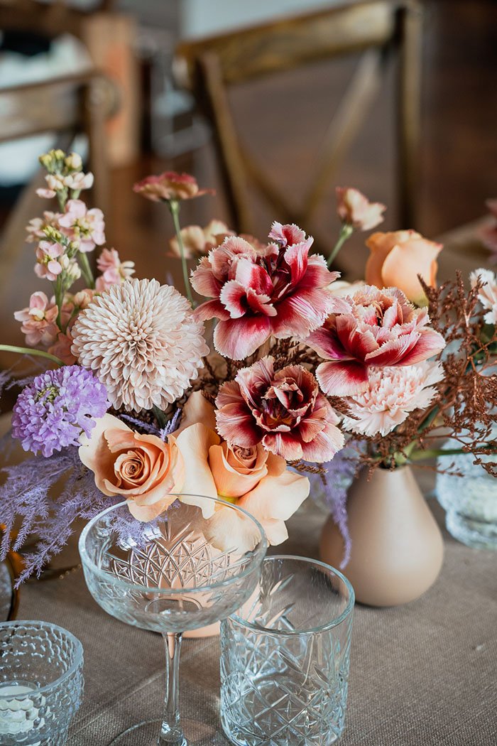 Ein Blumenbouquet steht auf einem Tisch mit Gläsern.