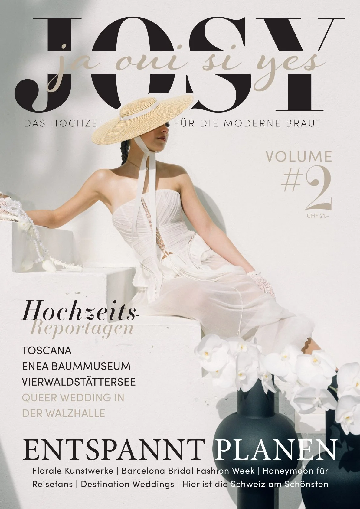 Eine Frau in einem weissen Kleid sitzt auf einer weissen Treppe mit einem Sonnenhut.