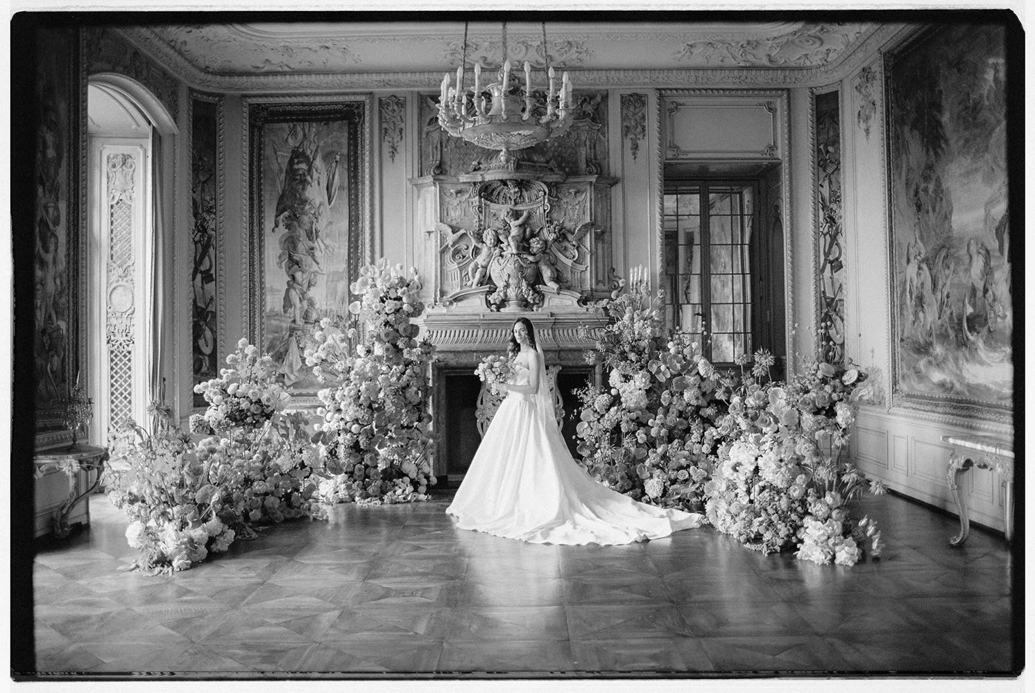 Eine Braut steht in einem Raum umgeben von vielen Blumen.