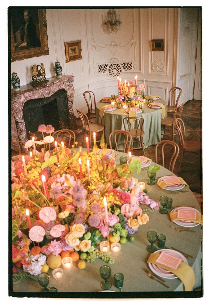 Ein eingedeckter Tisch mit vielen farbigen Blumen und Stabkerzen.
