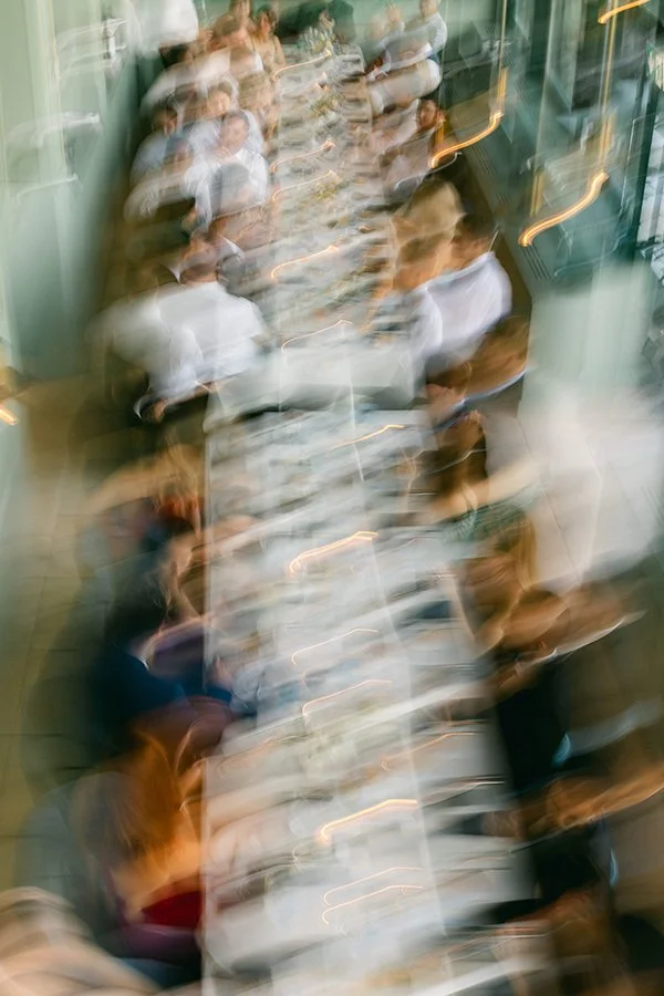 Ein unscharfes Bild von einem langen Tisch mit vielen Leuten.