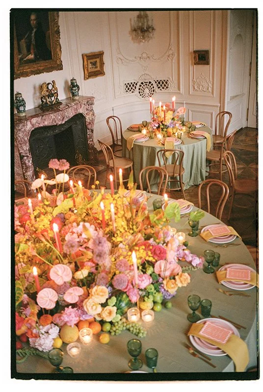 Zwei hellgrüne eingedeckte Tische sind mit vielen bunten Blumen dekoriert.