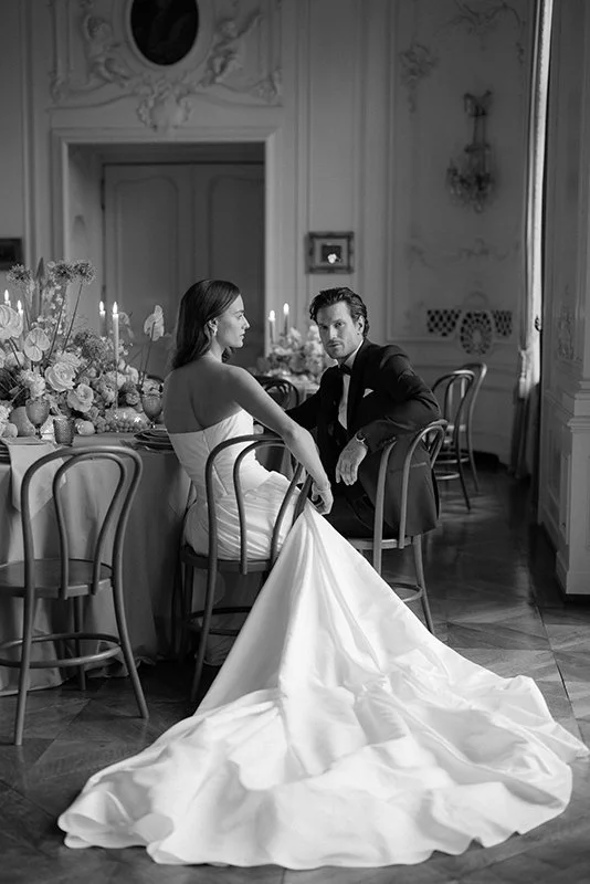 Ein Brautpaar sitzt an einem eingedeckten Tisch.