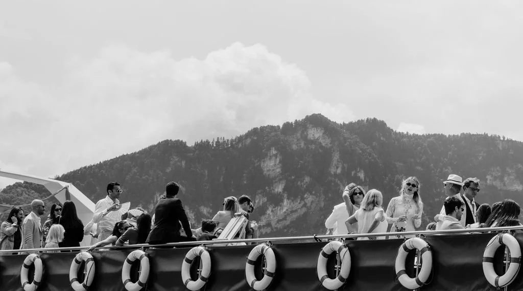 Viele Leute stehen auf einer Terrasse vor einem Berg.