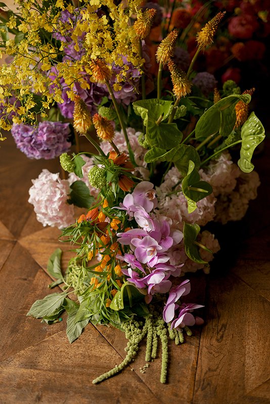Verschiedene bunte Blumen sind zu einem Bouquet auf einem Holzboden arrangiert.