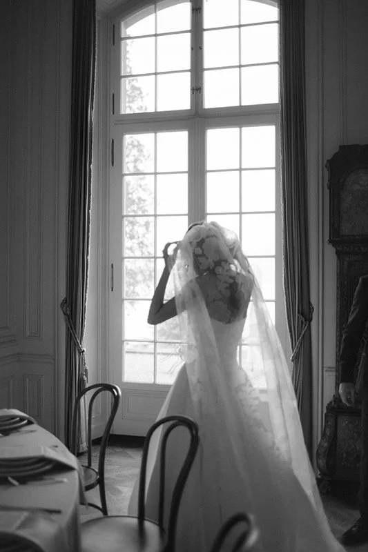 Eine Frau im Brautkleid läuft in einen Raum und hält ihren Schleier.