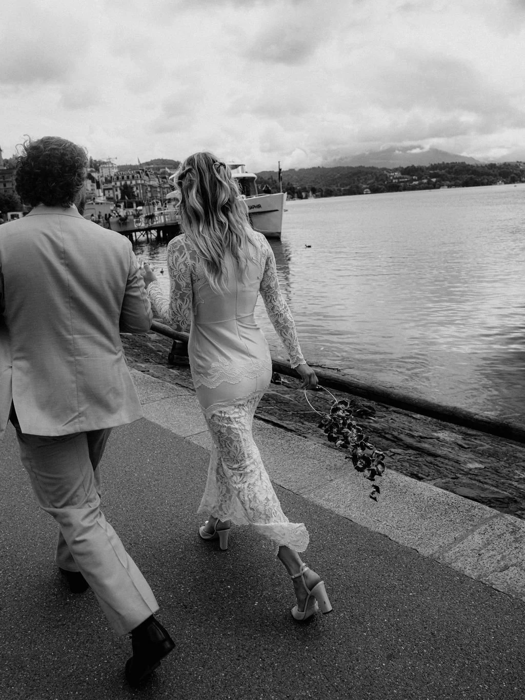 Ein Paar läuft Hand in Hand entlang von einem See.