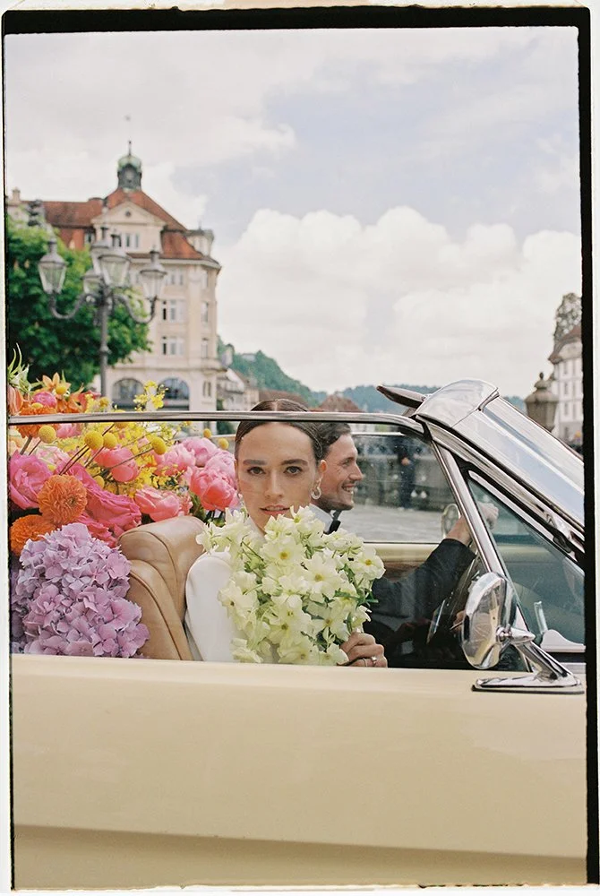 Eine Frau sitzt in einem Cabrio mit einem Blumenstrauss.