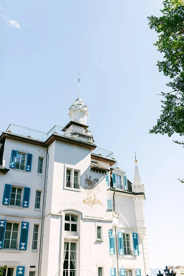 Ein weisses Haus mit blauen Fensterläden steht im Sonnenlicht.
