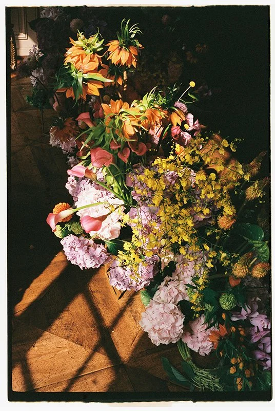 Ein Blumenarrangement aus bunten Blumen steht im Sonnenlicht am Boden.