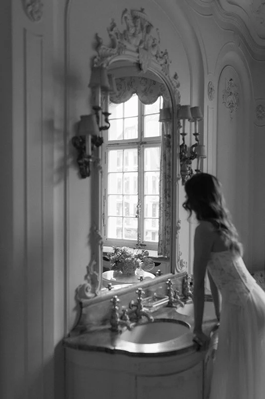 Eine Frau steht vor einem Spiegel in einem alten Bad.