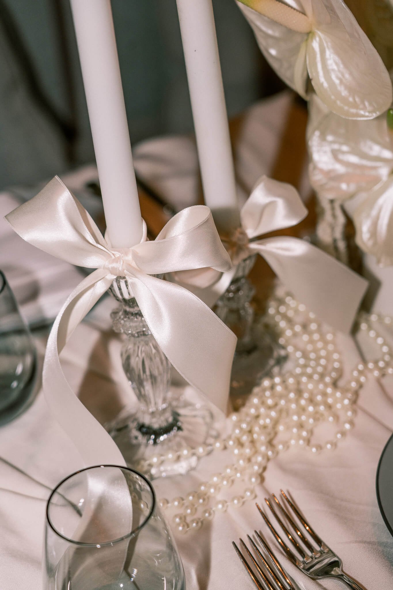 Ein glasiger Kerzenständer mit einer weissen Masche und einer weissen Stabkerze