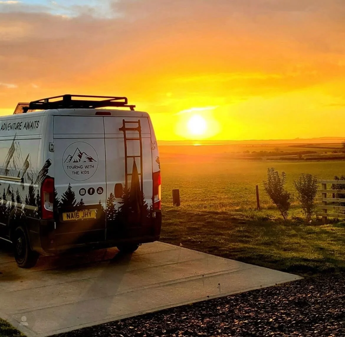 Camper van parked on a rural road at sunset with scenic landscape