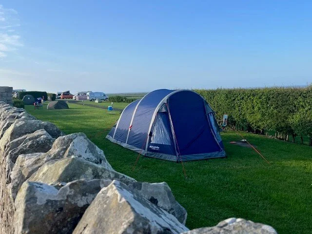 Campsite with blue tent and stone wall