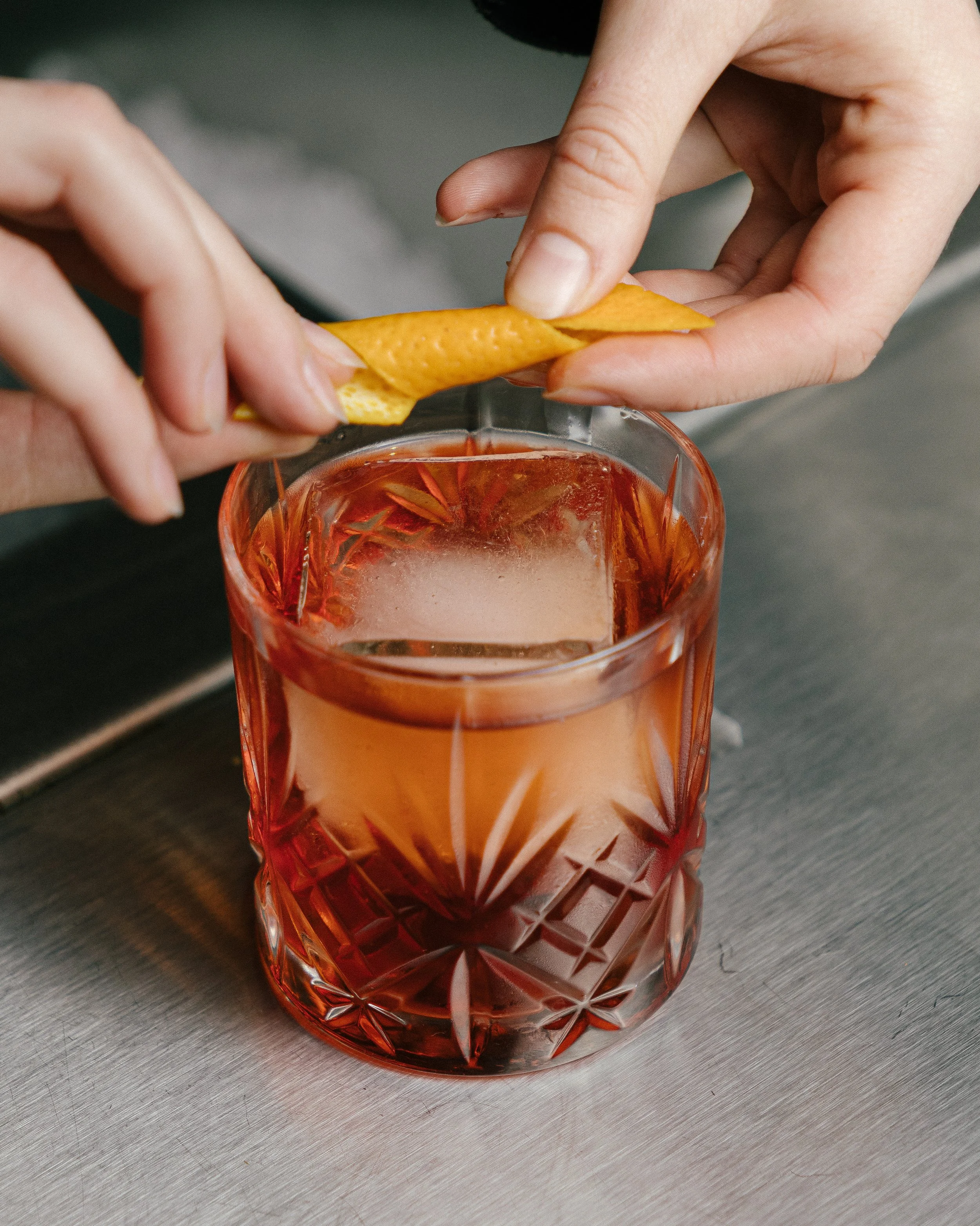 Un verre en cristal rouge profond rempli d'une boisson rouge, posé sur une surface en bois.
