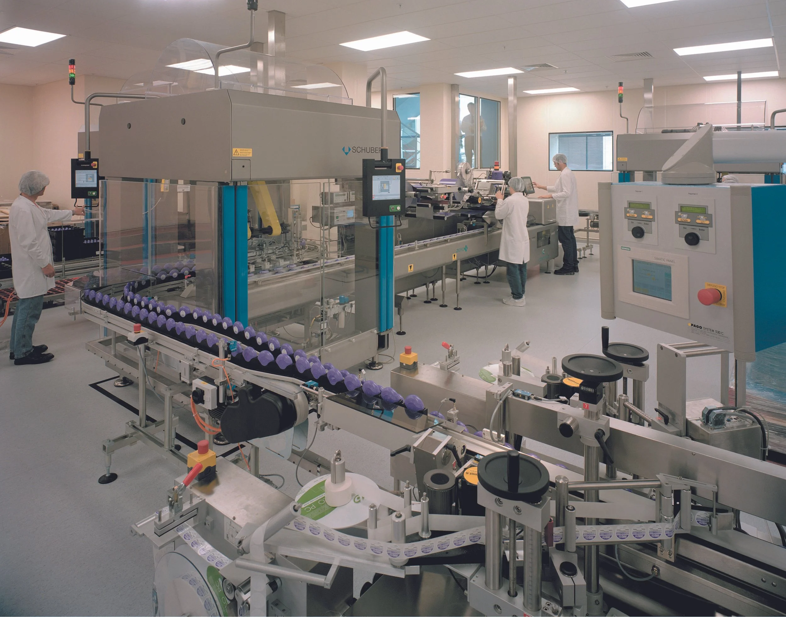 Pharmaceutical manufacturing facility with automated packaging machinery and workers.