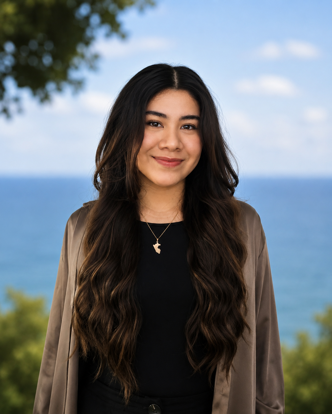 A young woman with long, wavy brown hair wearing a black top, brown jacket, and a necklace with a map of Africa pendant, smiling against a light blue background.