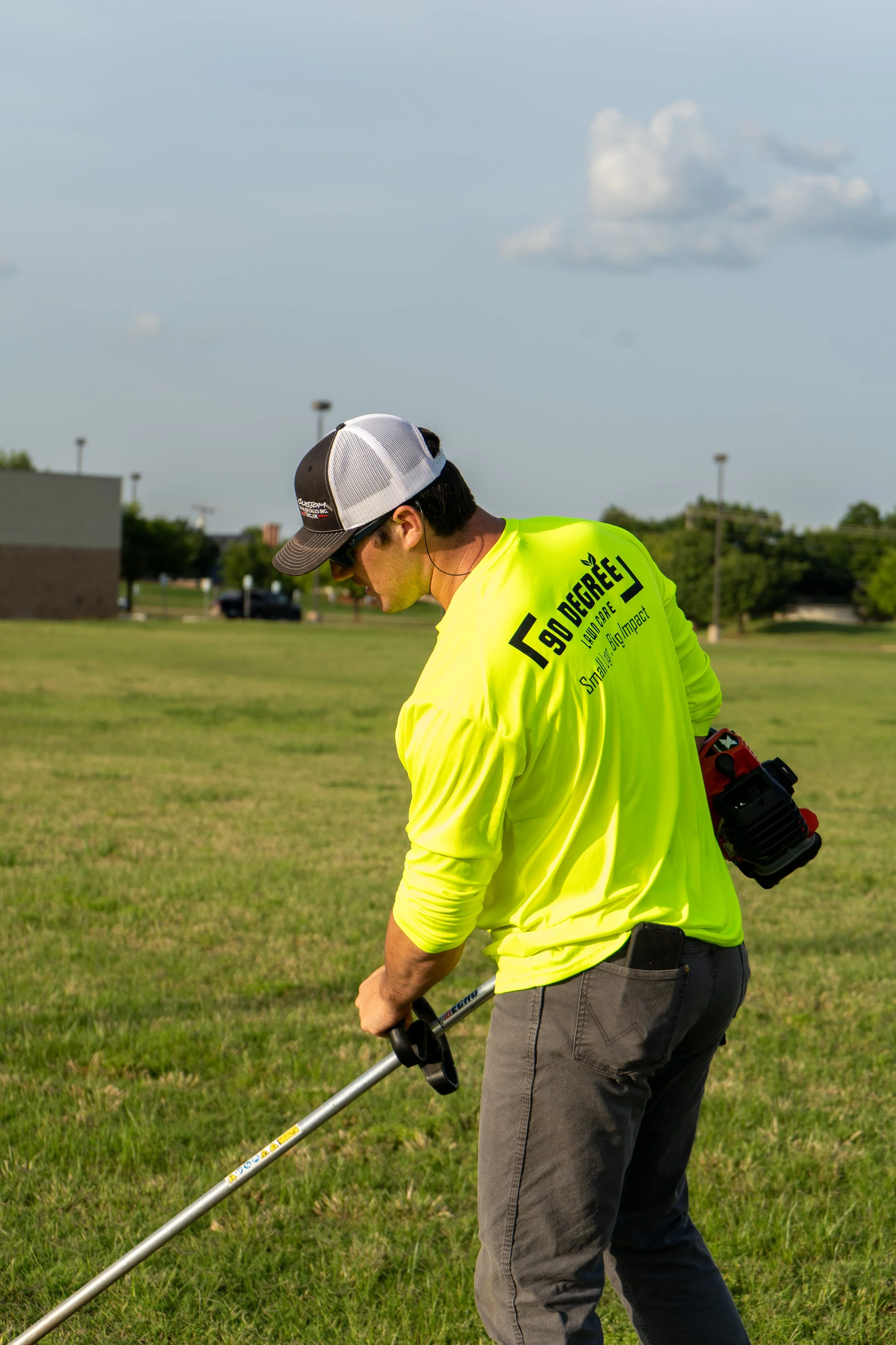 a man using a weedeater to cut a client in edmond oklahomas grass