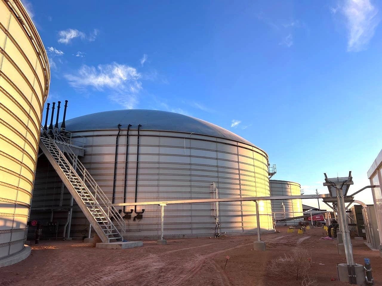 Large Biogas digester storage tanks with metal stairs, pipes, and equipment.