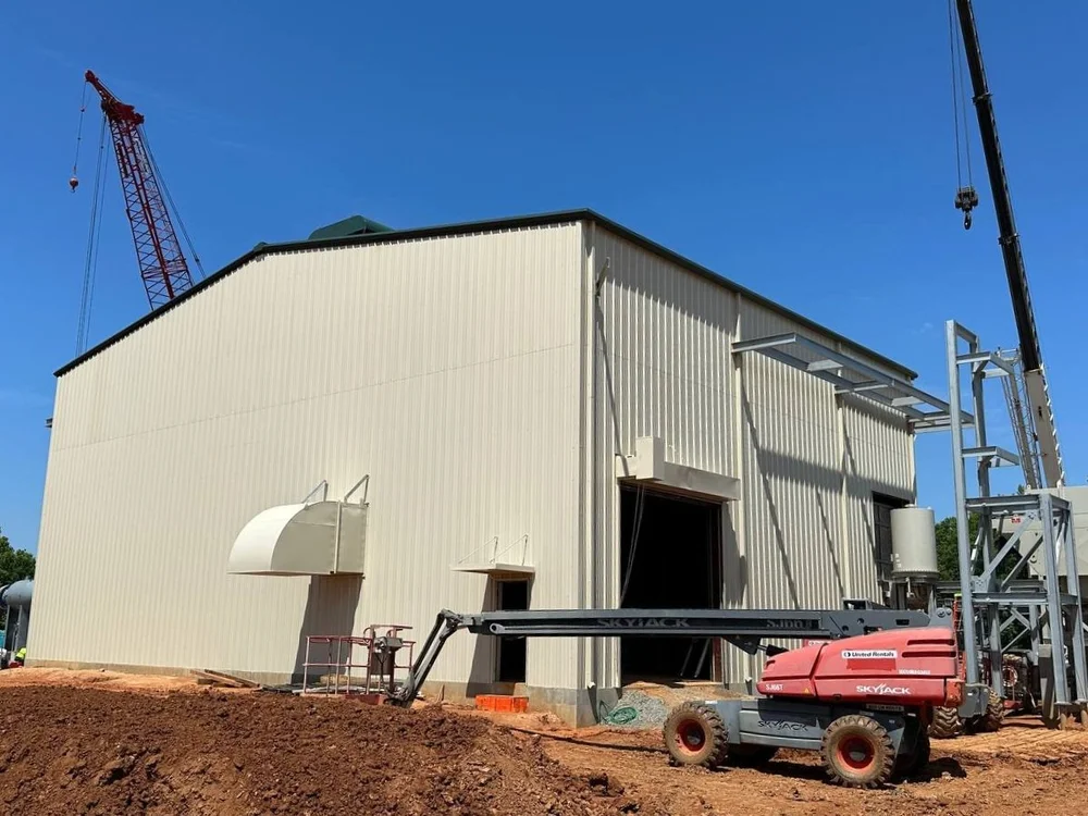 Metal building nearing completion with crane on site