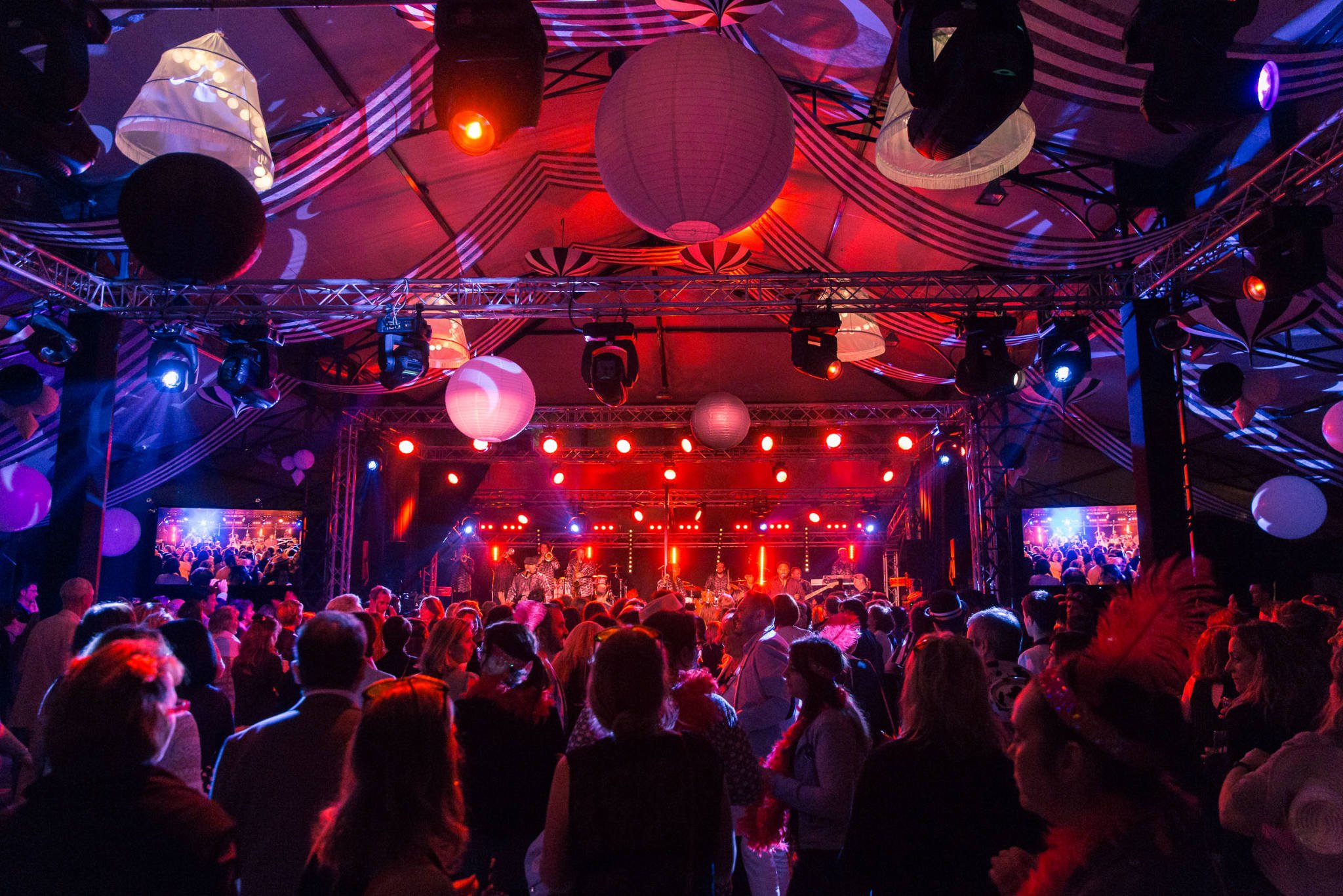 Crowd attending a lively indoor concert with colorful lighting and decorative paper lanterns.
